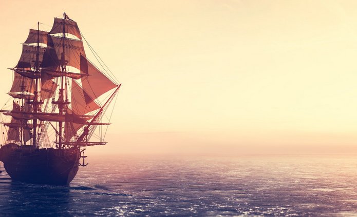 Pirate ship sailing on the ocean at sunset statek